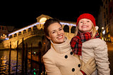 Happy mother and daughter near Rialto Bridge in Christmas Venice