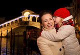 Daughter kissing mother near Rialto Bridge in Christmas Venice