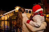 Seen from behind, mother and daughter looking on Rialto Bridge
