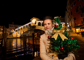 Woman holding Christmas tree near Rialto Bridge in Venice, Italy