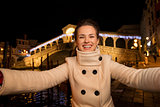 Woman taking selfie near Rialto Bridge in Christmas Venice