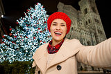 Happy woman taking selfie near Christmas tree in Florence, Italy