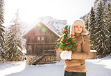 Woman with Christmas tree standing in front of mountain house