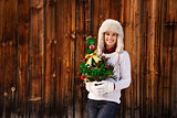 Happy woman with Christmas tree in the front of rustic wood wall