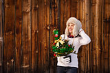 Woman with Christmas tree near rustic wall looking copy space