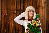 Woman with Christmas tree near rustic wall looking on copy space
