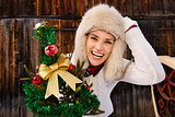 Young woman with Christmas tree in the front of rustic wood wall