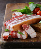 smoked bacon with basil and tomatoes on a cutting board