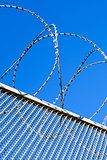Fence with a barbed wire against the blue sky. 