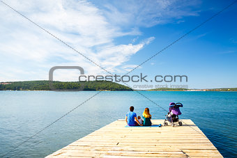 Family with Little Baby Sitting on Pier near the Sea