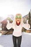 Woman in Christmas glasses showing thumbs up near mountain house