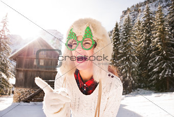 Woman in Christmas glasses pointing on something in countryside