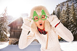 Merry woman in a Christmas glasses in front of a mountain house