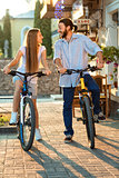 happy young couple of bicyclists talking in the street
