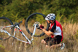 Man cyclist repairing a bike  against green nature