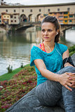Sporty female with mp3 player sitting in front of Ponte Vecchio