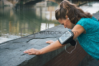 Young woman in sportswear and with mp3 catching breath