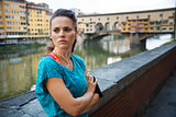 Young woman in sportswear is staying next to Ponte Vecchio