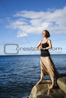 Woman meditating by ocean.