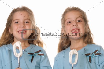 shot of twin girls with cake beaters