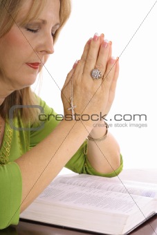 shot of a woman praying over the bible with rhinestone cross