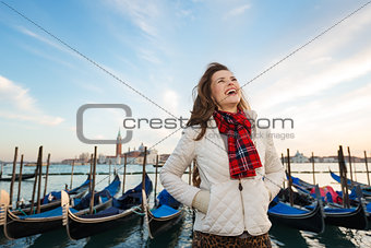 Happy woman traveler standing on embankment in Venice, Italy