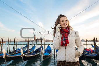 Woman traveler speaking smartphone on embankment in Venice