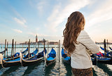 Seen from behind, woman traveler standing on embankment, Venice