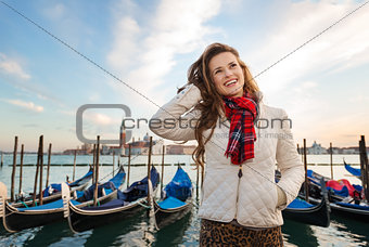 Happy young woman traveler standing on embankment in Venice