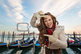 Woman traveler framing with hands on embankment in Venice, Italy