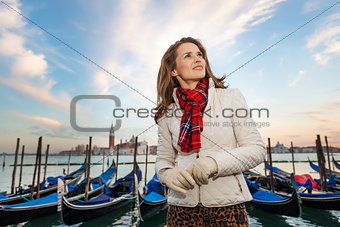 Dreamy young woman traveler standing on embankment in Venice