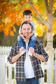 Mixed Race Boy Riding Piggyback on Shoulders of Caucasian Father