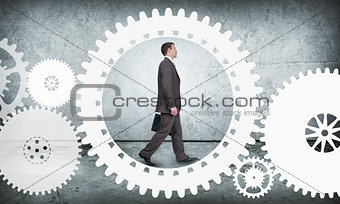 Businessman walking in cog wheel, side view