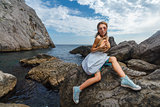 Young teen posing on stones at sea fashion photoshoot