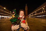 Woman with Christmas tree and gift standing on Piazza San Marco