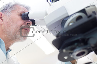 Senior scientist  microscoping in lab.