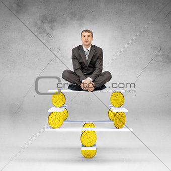 Businessman sitting on balance with gold coins
