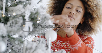 Pretty young woman decorating a Christmas tree