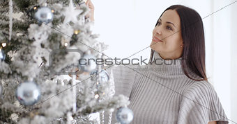 Pretty young woman decorating her Christmas tree