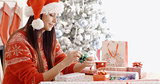 Young woman sitting wrapping Christmas gifts