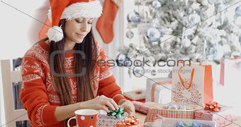 Young woman decorating her Christmas gifts