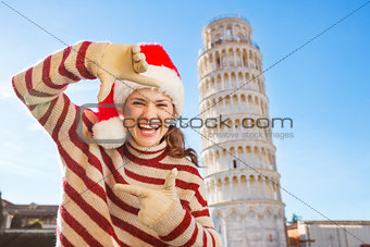 Woman in Santa hat framing with hands near Leaning Tour of Pisa