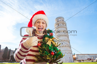 Woman with Christmas tree showing thumbs up near Leaning Tour