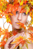 Beautiful woman wrapped in autumn leafs
