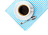 White coffee cup with saucer and spoon tableware on blue chequered napkin