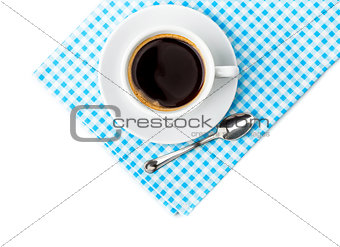 White coffee cup with saucer and spoon tableware on blue chequered napkin