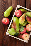 Pears and apples in wooden box on table