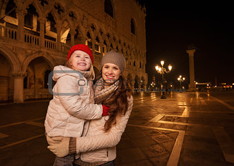 Mother and child standing on Piazza San Marco in the evening