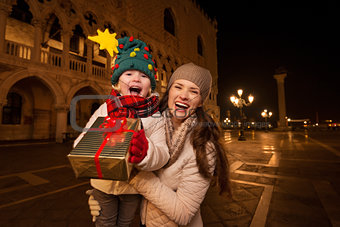 Happy mother and child showing Christmas gift box in Venice