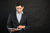 indian business male using tablet in black background